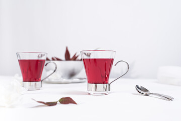 Dos tazas transparente de té de bayas sobre una mesa blanca y un fondo gris claro	