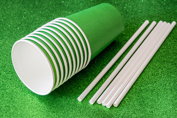 Recycled cardboard cups and straws, on bright green background.