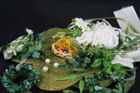 Ostermotive auf schwarzem Hintergrund. Osterdekorationen in Nahaufnahme. Weidenkranz mit bunten Eiern. Arrangement in Eierschale auf Stroh. Tonei mit Huhn darin. Symbole des Lebens und des Gl&uuml;cks.
