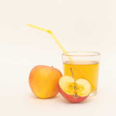 a glass of apple juice with straws and a little apples isolated on white background.