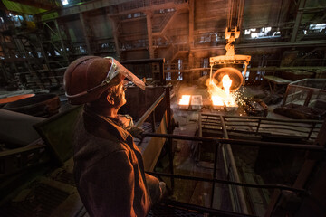 Steelworker when pouring liquid metal from tanks in the molds at a steel mill. - 496161851