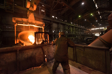 Steelworker at work near the tanks with hot metal - 496161853