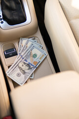 A dollar bills in the male hand on the background of the steering wheel in the car. Concept of earnings or bribes, insurance or credit
