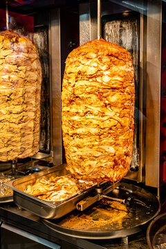 ..Delicious slabs of skewered fast food shawerma chicken and lamb meat turn side by side on a spit.