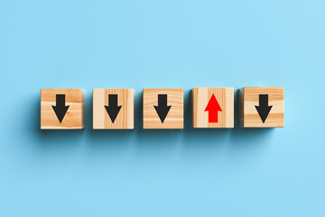 Wooden blocks with arrows with one stand out from the crowd and moving up on a blue background. Concept of innovation, solutions, uniqueness, individuality and thinking differently. 3d rendering.