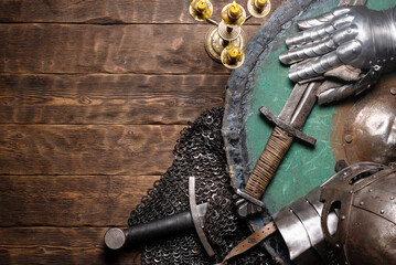 Medieval armor, shield and weapon on the wooden flat lay table background with copy space.