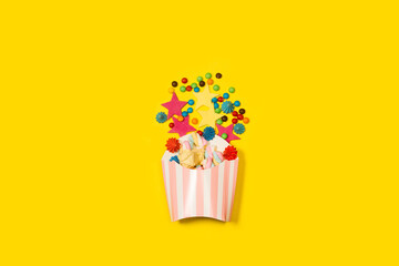 Malvaviscos, merengues y dulces de caramelo junto a un cono de cartón sobre un fondo amarillo...