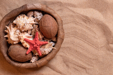 Seashells in a wicker basket on the sand. Summer holidays at sea background with space for text....