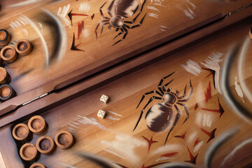 Backgammon playing field with dice and chips. In the field the image of a spider. The game is made of wood in brown tones. Game concept. Board game. Dice and checkers on the backgammon playing field.