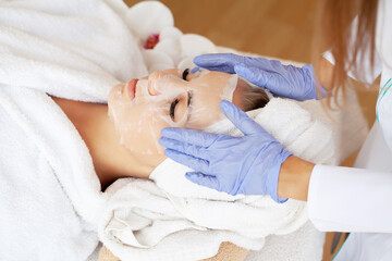 Obraz na płótnie Canvas Cosmetologist applying sheet mask on woman in spa salon