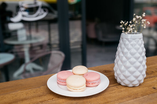 Macaroons in a plate on a background of cafes. Macaroons on a wooden table.