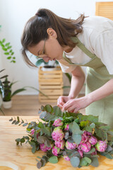 Professional florist makes a bouquet for a client in a store. Floral arrangement