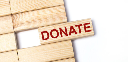 On a light background, wooden blocks with the text DONATE. Close-up top view.