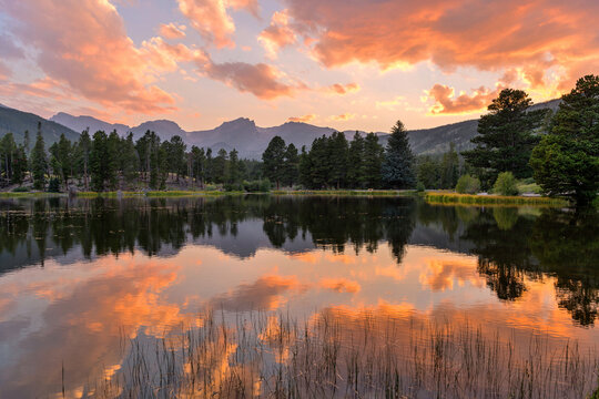Summer Sunset at Sprague Lake - A panoramic Summer sunset view at Sprague Lake, with high peaks of Continental Divide rising at shore, Rocky Mountain National Park, Colorado, USA.