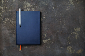 Photo of blank blue notebook with pen on concrete background. Top view with copy space. Flat lay.
