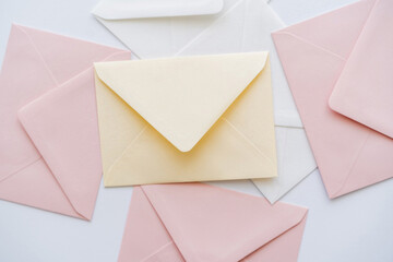 top view of pastel envelopes on white. - obrazy, fototapety, plakaty