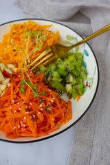 Multicolored vegetable salad in a white plate with a golden fork on a linen napkin top view vertical photo