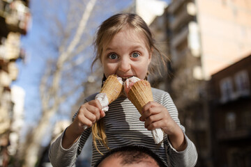 Little girl is eating ice cream and having fun at the street.