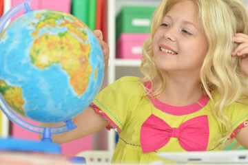 Fototapeta premium cute girl with globe sitting at desk