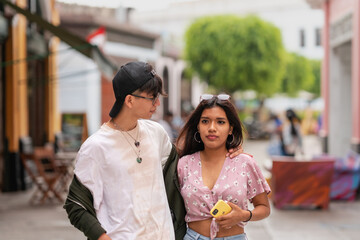 Two young friends embracing while walking together in a city street