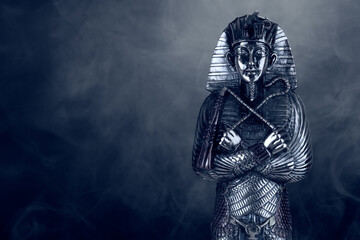 Fototapeta na wymiar steel figurine of the pharaoh on a black background with smoke
