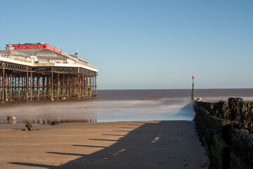 Selective focus on sea defences on Cromer beach, with an out of focus Cromer Pier as backdrop. North Norfolk, UK