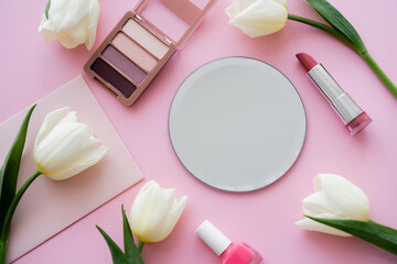 Obraz na płótnie Canvas top view of white tulips on envelope near decorative cosmetics on pink.