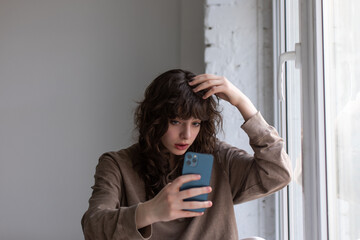 Attractive young woman with curly hair takes selfie.