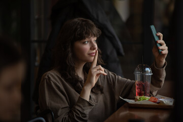 Young woman taking a selfie while sitting in a cafe.