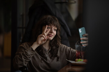 Young woman taking a selfie while sitting in a cafe.