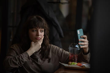 Young woman taking a selfie while sitting in a cafe.