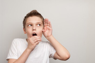 caucasian young boy dressed in the white t-shirt listening through the silence
