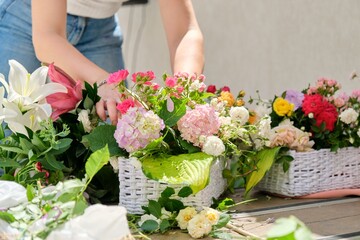 Obraz na płótnie Canvas Woman florist making flower arrangement in basket outdoor.