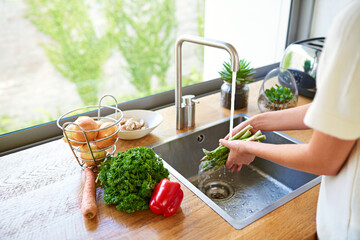 Prepping a delicious meal. Cropped shot of a woman washing vegetables in a kitchen sink.