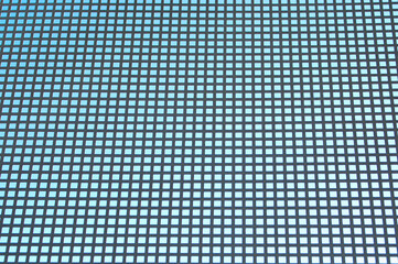 blue background, in the photo a metal grid with square cells on a blue background.
