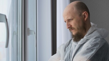 Doctors stand at the window adjusting the mask on his face. A man with a bald head is a laboratory assistant in a medical institution. Work in the hospital laboratory assistant biologist.