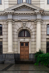 Entrance to the building. Dark brown wooden door. White building of classical style with pillars. Greek style of construction. Lviv railway station