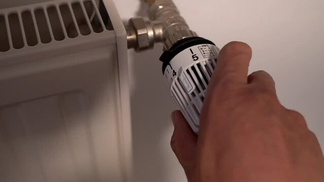 Thermostat wird gedreht um Energiekosten zu sparen.