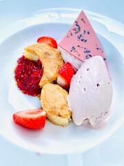 Tasty sweet strawberry smooth mousse dessert served in a white porcelain bowl. Summer food eating in restaurants. food porn fresh red fruit with pink chocolate jam compote. Delicious yummy flat lay.