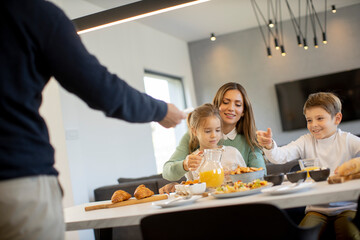 Young happy family talking while having breakfast at dining table