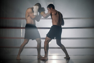 Obraz premium Two professional young muscular shirtless male boxers fighting in a boxing ring. High quality photography.