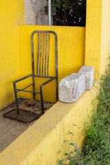 Rusty frame of a chair on the porch of a yellow house in Willemstad, Curacao