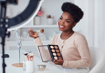 happy young african american woman streaming a beauty vlog from home, online content creator applying a makeup on