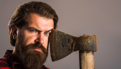 Bearded man with old axe near face. Brutal lumberjack hipster with ax. Closeup portrait.