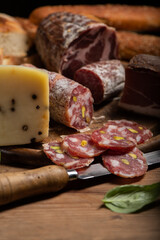 Cutting board with ham, salami, cheese, bread on a rustic wooden board