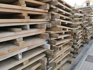Stacked old used wooden pallets on street. Stacks of Euro-type cargo pallets.