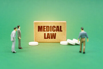 On the green surface are pills, miniature figures of people and a sign with the inscription - MEDICAL LAW