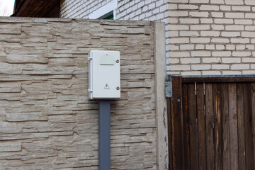 Anti-vandal box with a counter on the fence of a residential building. Inside the box is an electric meter.