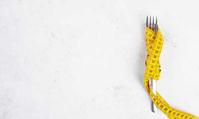 Fork  tight  with a tape measure, copy space for text, making a diet, loosing weight, staying...