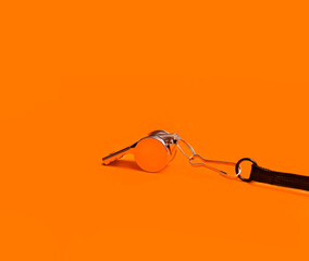 Sports whistle on orange background. Concept - sport competition, referee, statistics, challenge....
